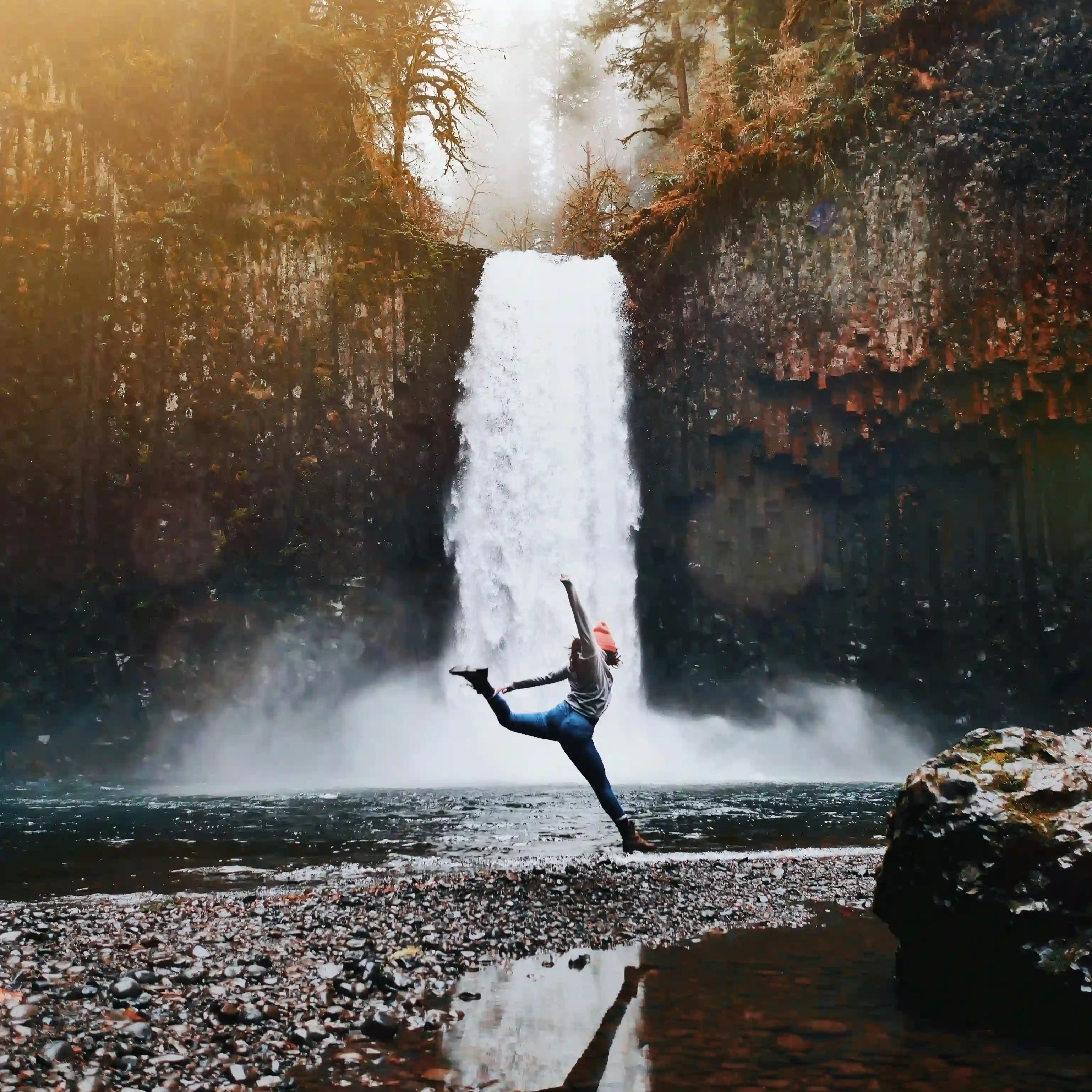 Frau macht Yoga vor Wasserfall
